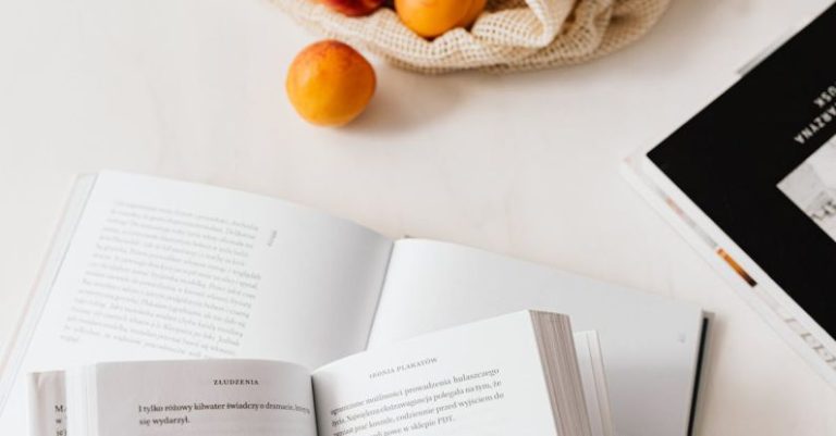 Product Pages - Jute sack with appetizing ripe apricots placed on table with different books