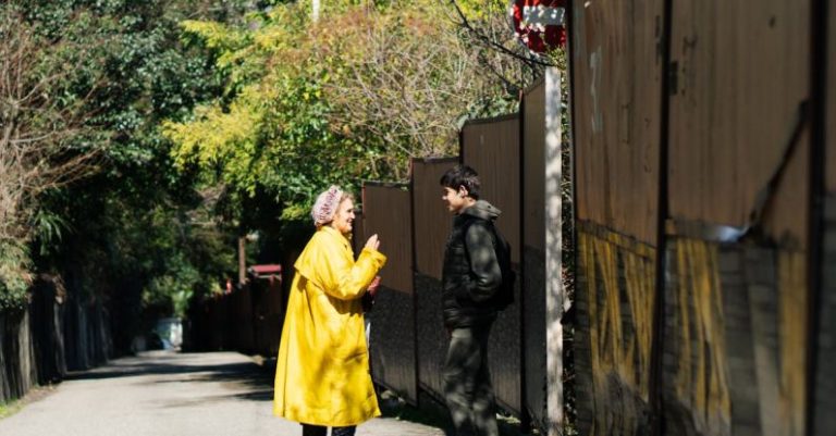 Conversions - A man and woman in yellow rain coats talking on a street