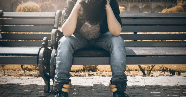 Problems - Man in Black Shirt and Gray Denim Pants Sitting on Gray Padded Bench